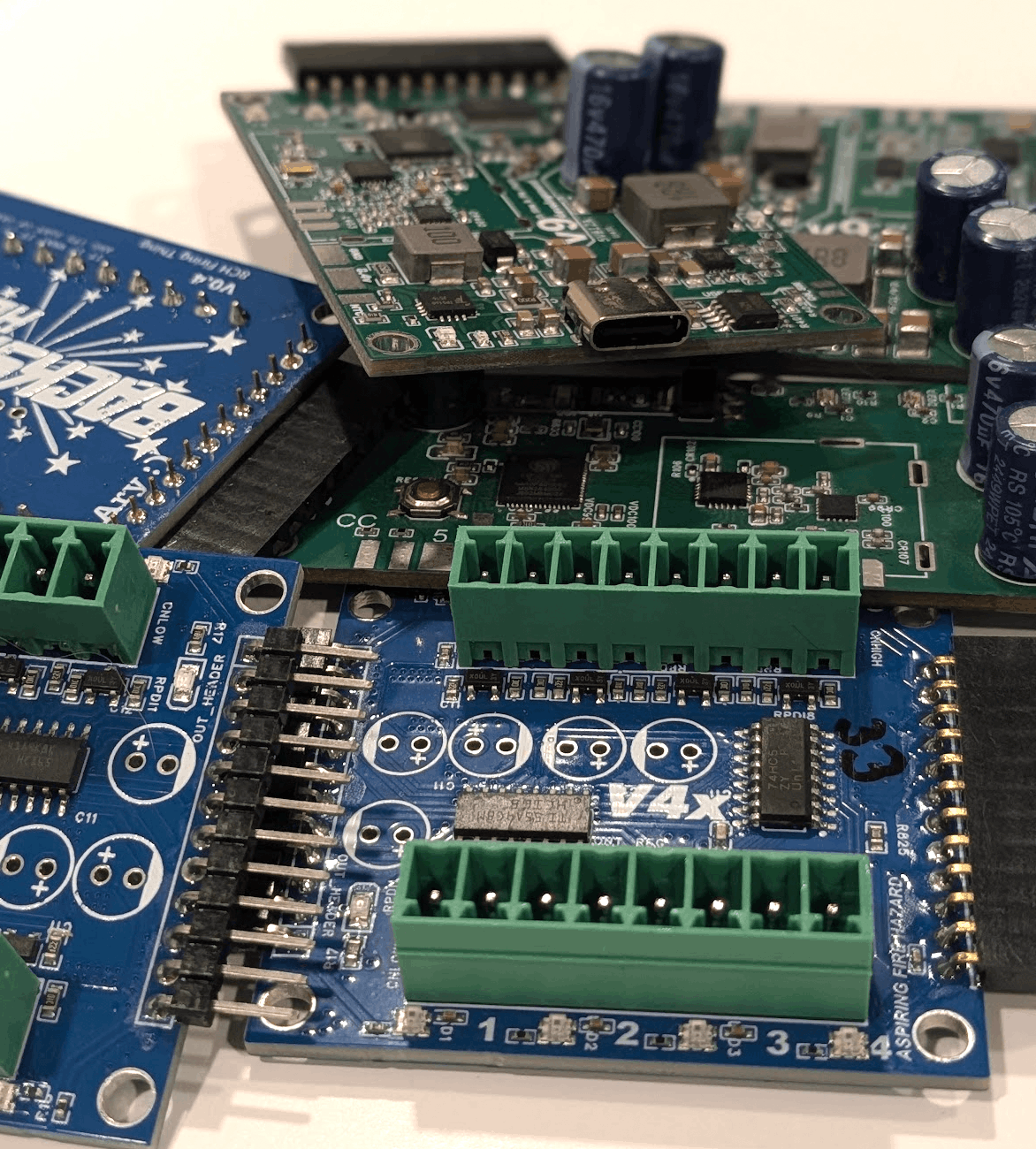 The Backyard Hero board family of receiver, dongle, and cue module stacked on a workbench